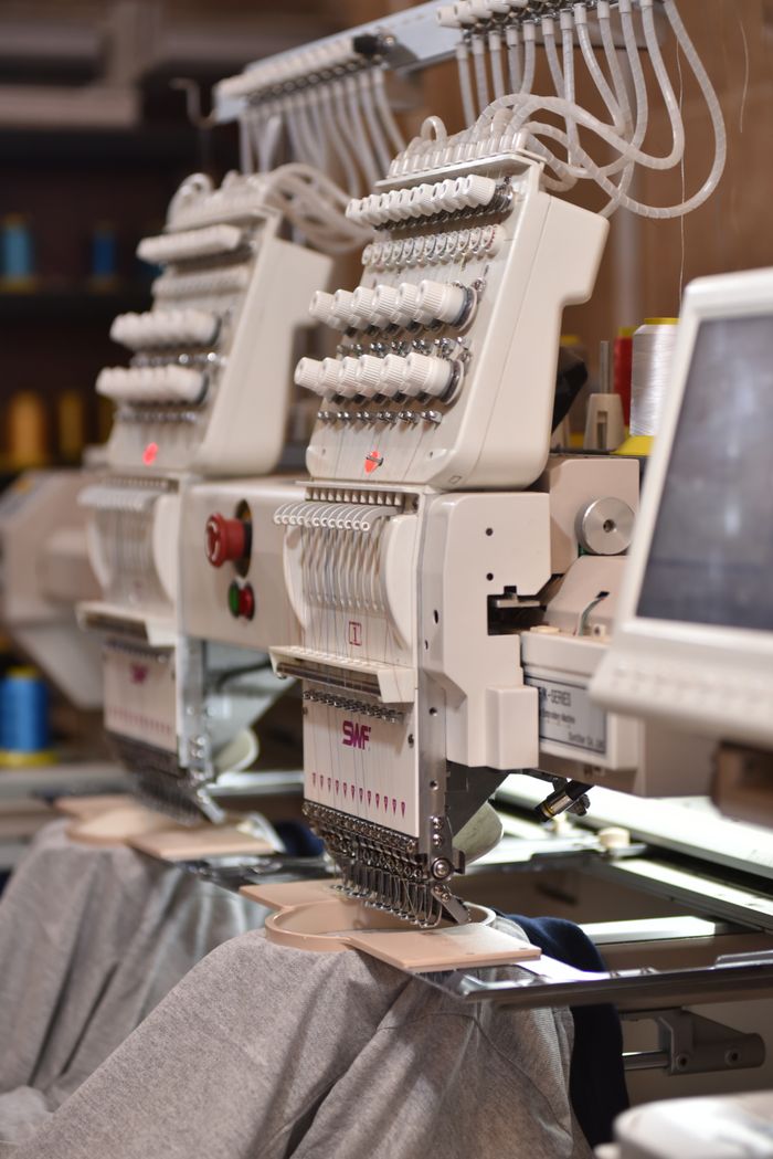 gallery-01 Close-up of automated industrial sewing machines stitching fabric in a factory setting.