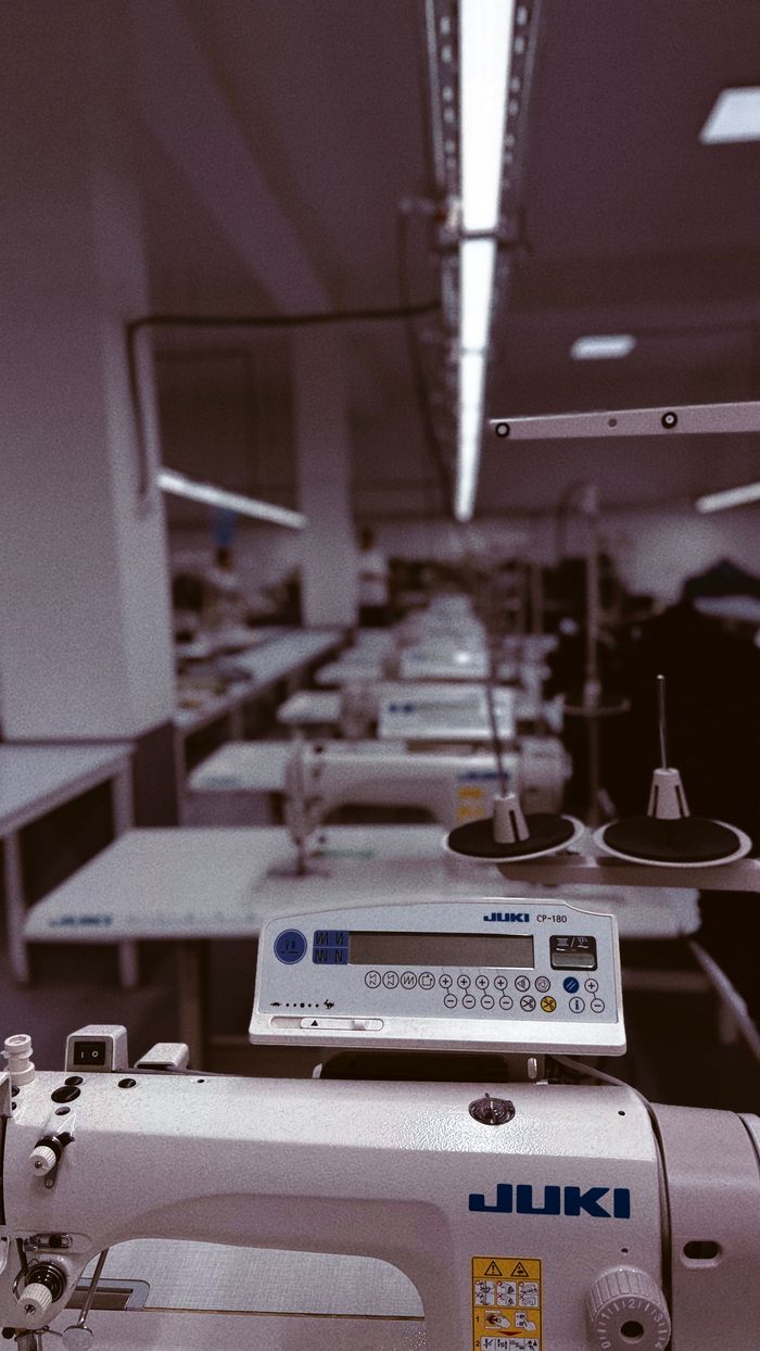 gallery-02 A row of industrial sewing machines in a factory setting in Uzbekistan, highlighting modern textile production.